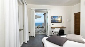 A hotel room with a bed, a desk, and a painting of a sunset over the sea. - Villa Orleans (Amalfi)