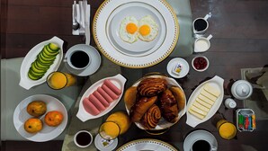 Une table de petit-déjeuner avec des assiettes d’œufs, de viennoiseries et des fruits.