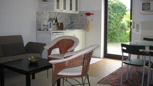 Ein kompakter Wohnraum mit Küchenzeile, Essbereich und Sitzecke mit Sofa und Sesseln.