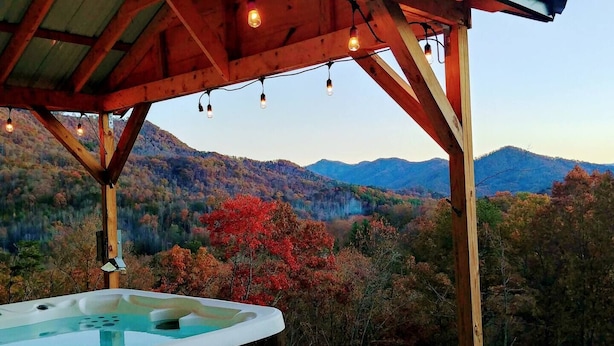 Un bain à remous sous une pergola en bois, avec une vue imprenable sur un paysage montagneux.
