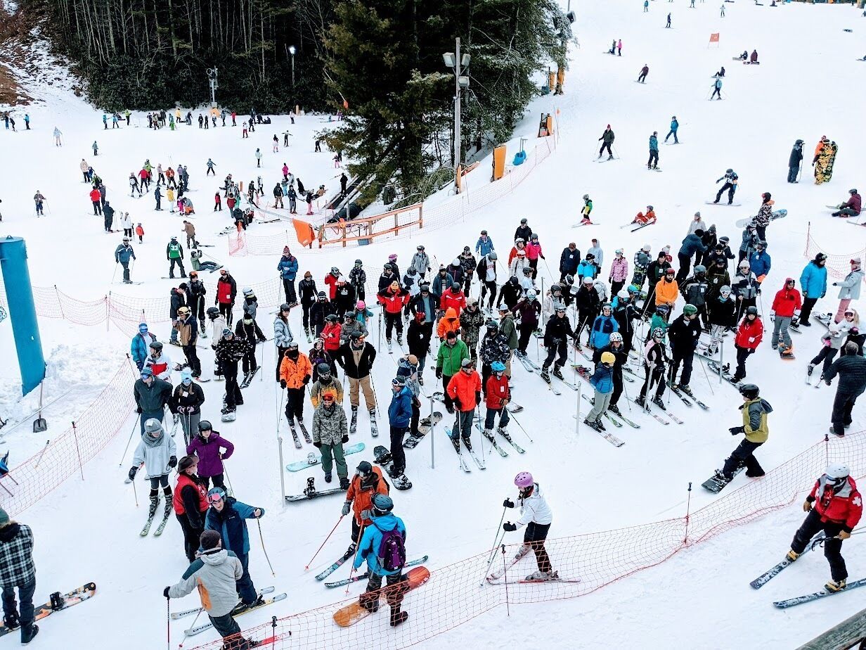 A crowded ski slope with skiers and snowboarders.