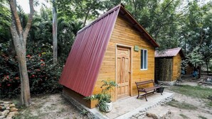 A small wooden cabin with a red roof, a wooden door, and a bench outside. - Casa Campomar (Juan de Acosta)