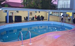 Una piscina al aire libre, sillones reclinables de piscina