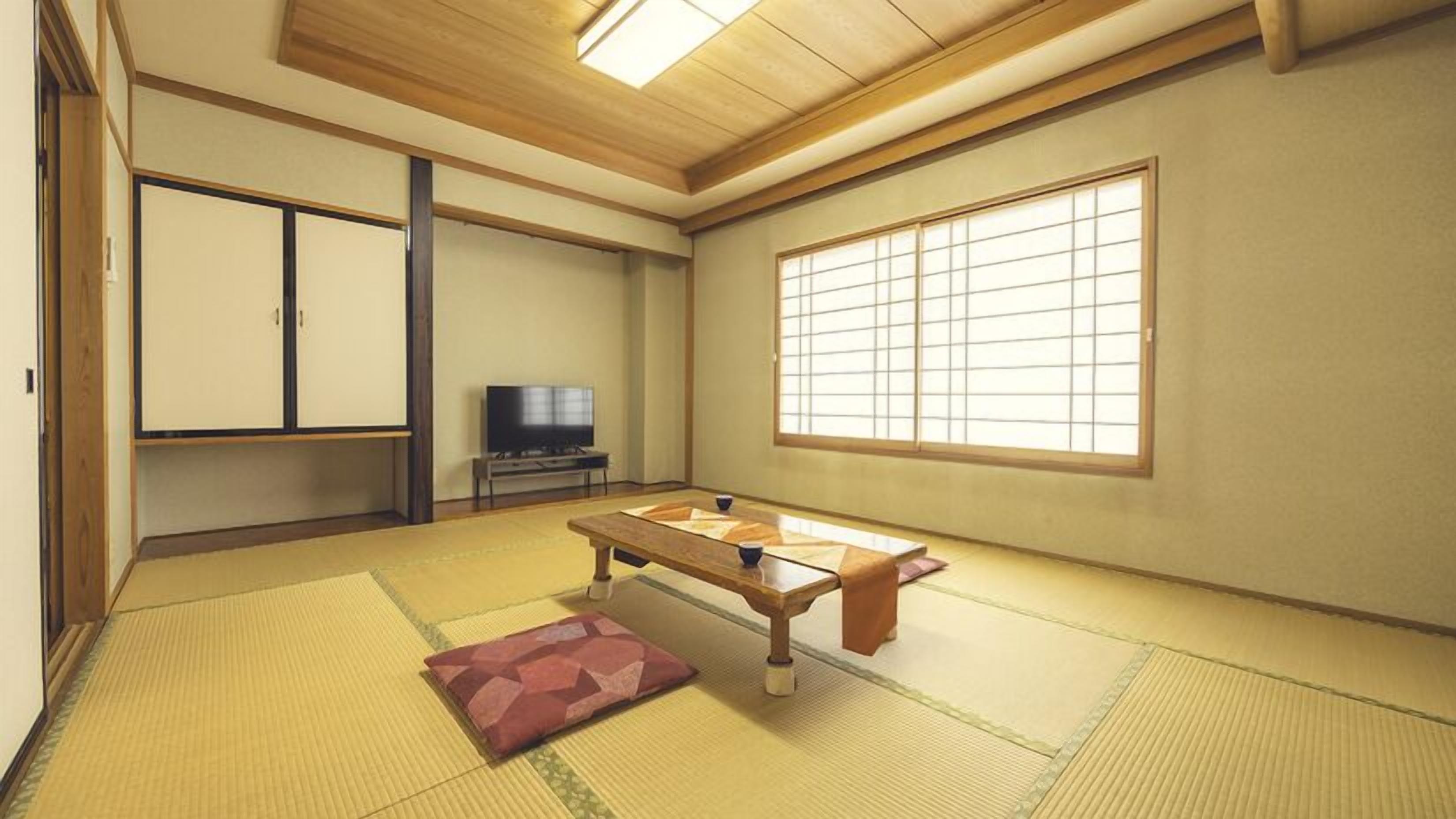 Una habitación japonesa tradicional con suelo de tatami, una mesa baja, un televisor y puertas correderas.
