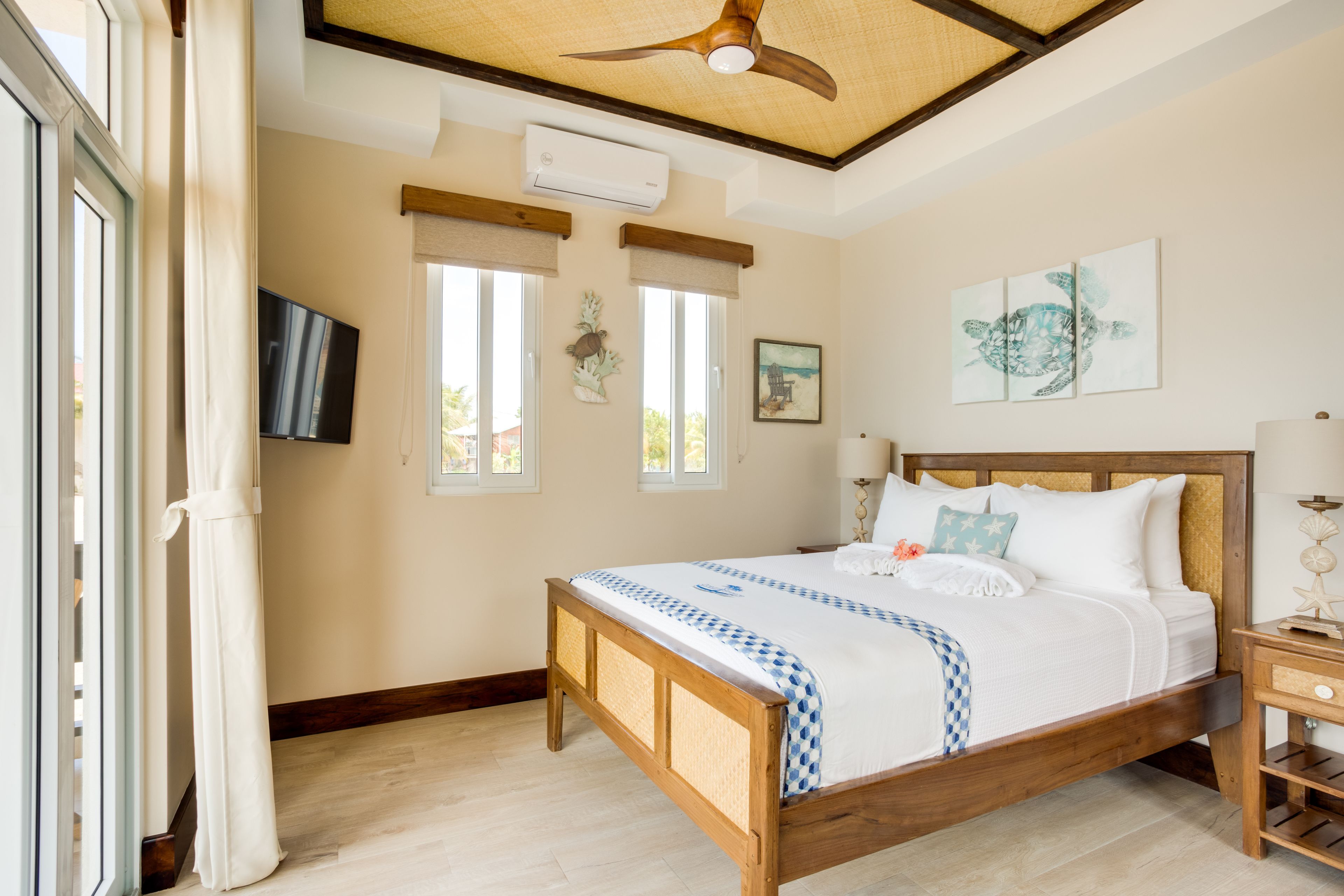 Un dormitorio con cama de madera, ventilador de techo y una ventana grande con vistas al exterior.
