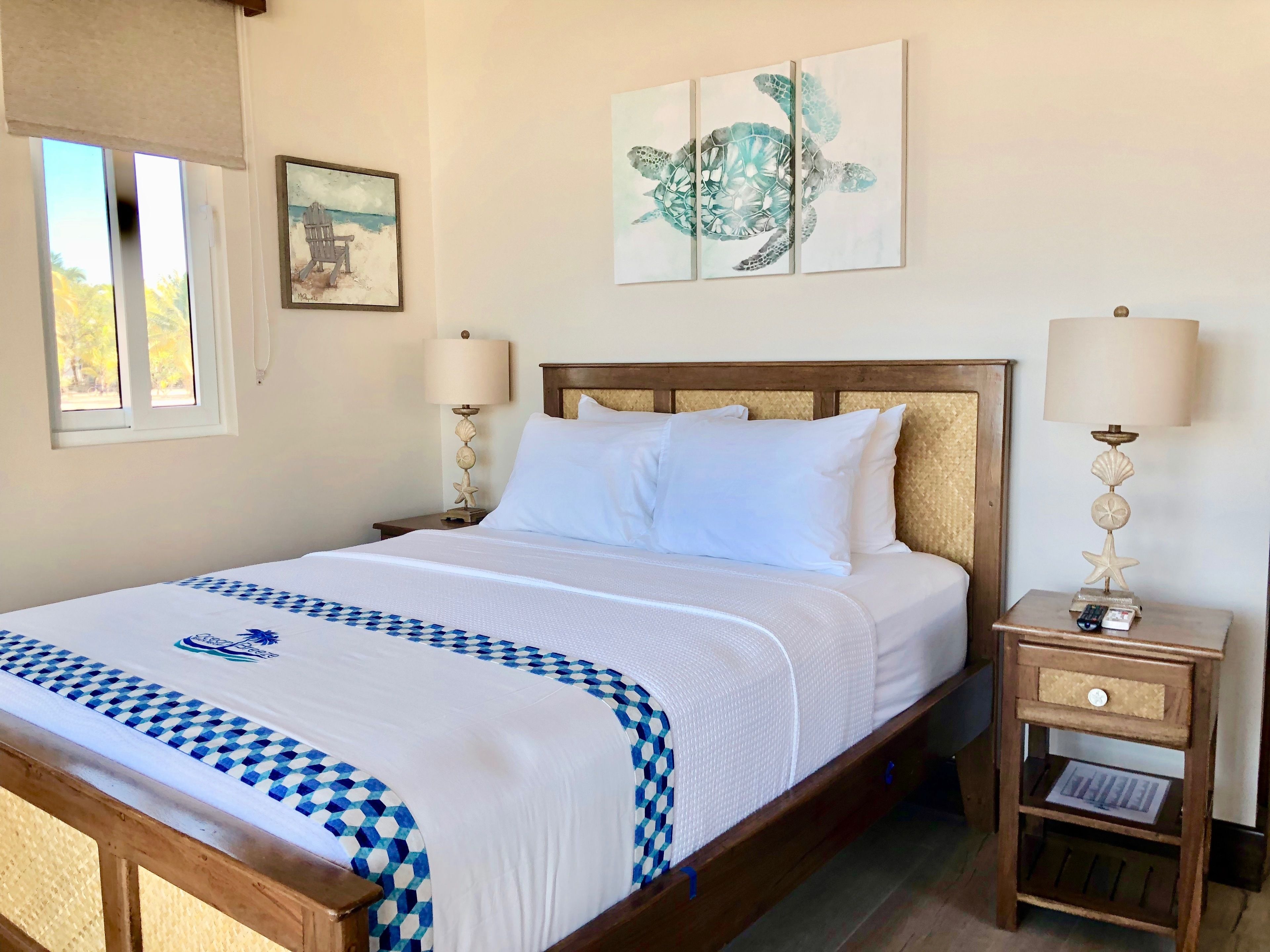 A neatly made bed with a blue and white checkered bedspread, a wooden headboard, and two bedside lamps with decorative shells.