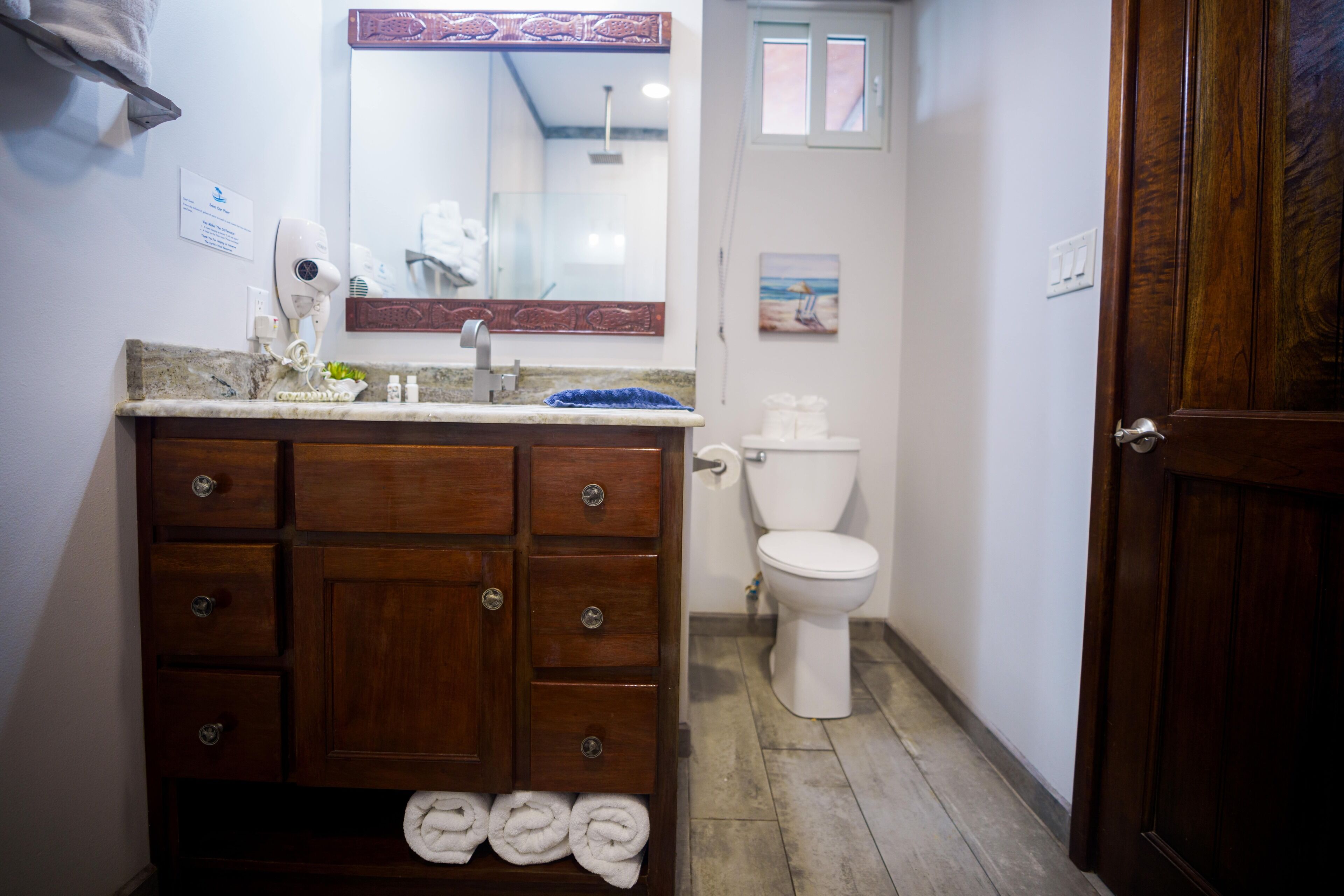 Un baño con tocador de madera, inodoro blanco y un perchero con toallas.