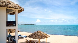 A beachside structure with a thatched roof, wooden lounge chairs, and a view of the sea. - Ocean Breeze (Placencia)
