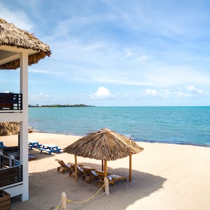 A beachside structure with a thatched roof, wooden lounge chairs, and a view of the sea.