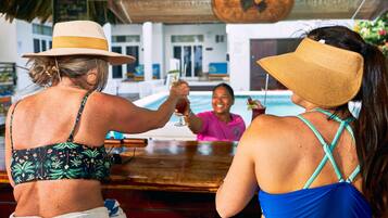 Two people at a bar with a pool in the background.