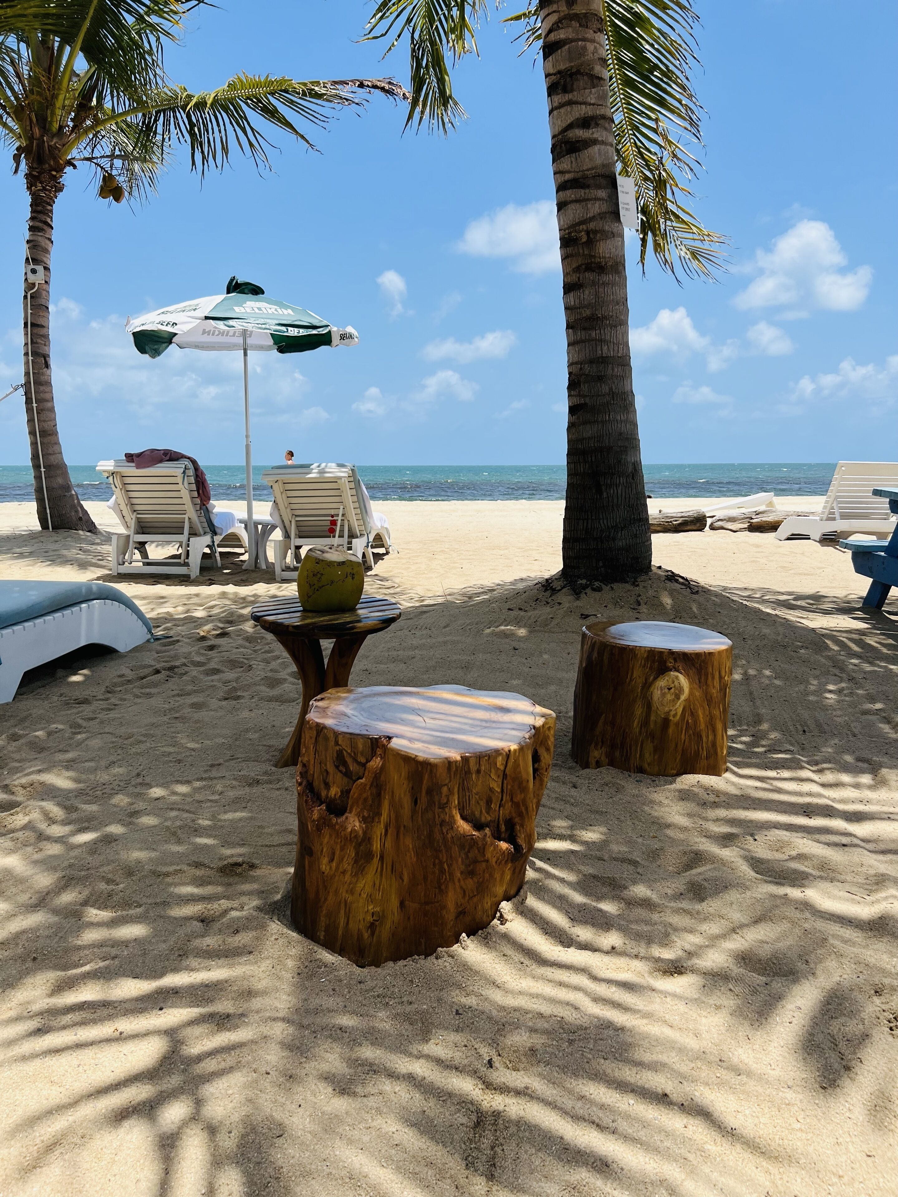 Eine Strandkulisse mit Liegestühlen, einem Tisch und einem Baumstumpf.