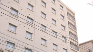 A multi-story hotel with a red and beige facade, a blue entrance, and a visible sign for the hotel. - Regaro Hotel Miyazaki (Miyazaki)