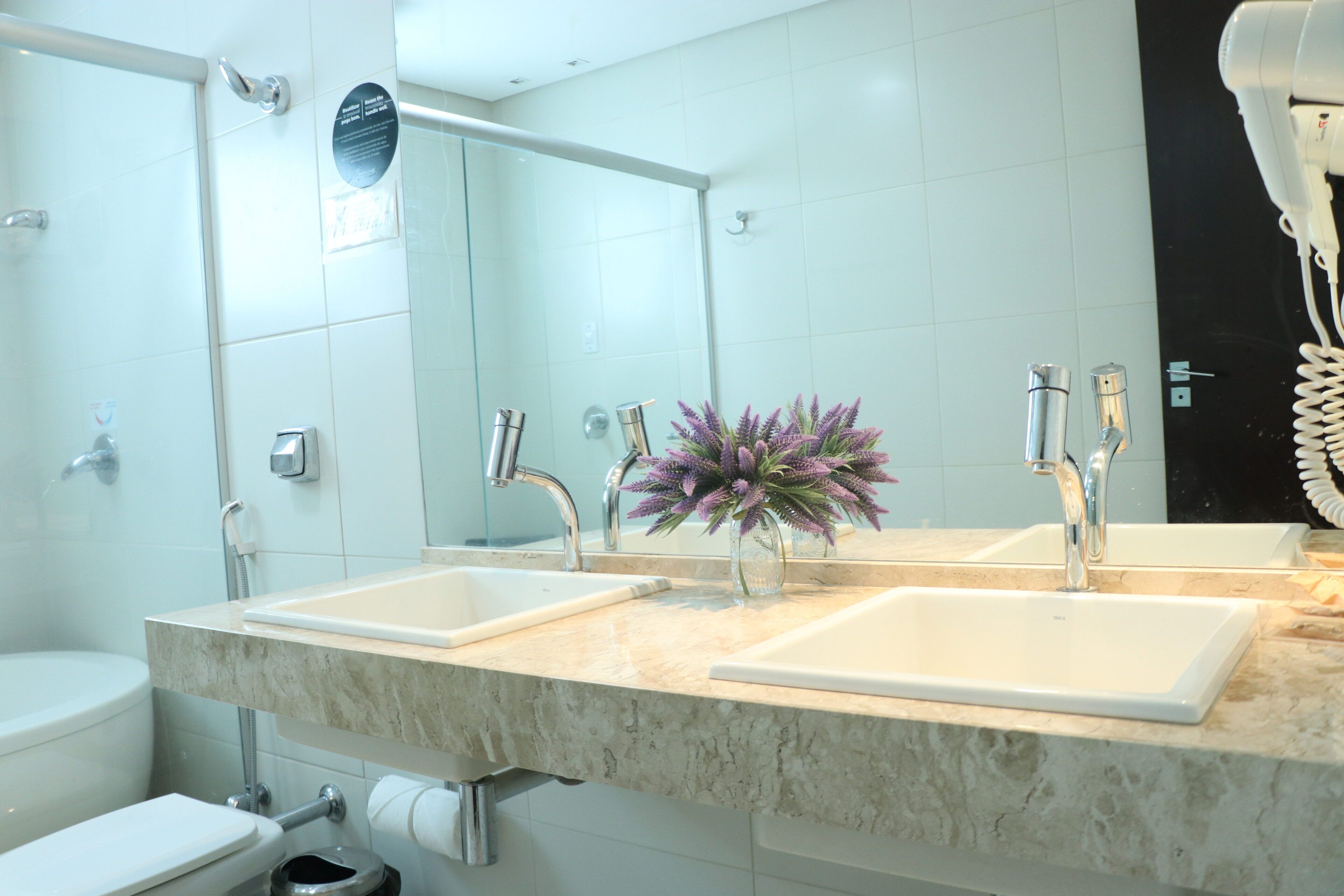 Un baño moderno con dos lavamanos, un espejo grande y un secador de pelo sobre el mostrador.