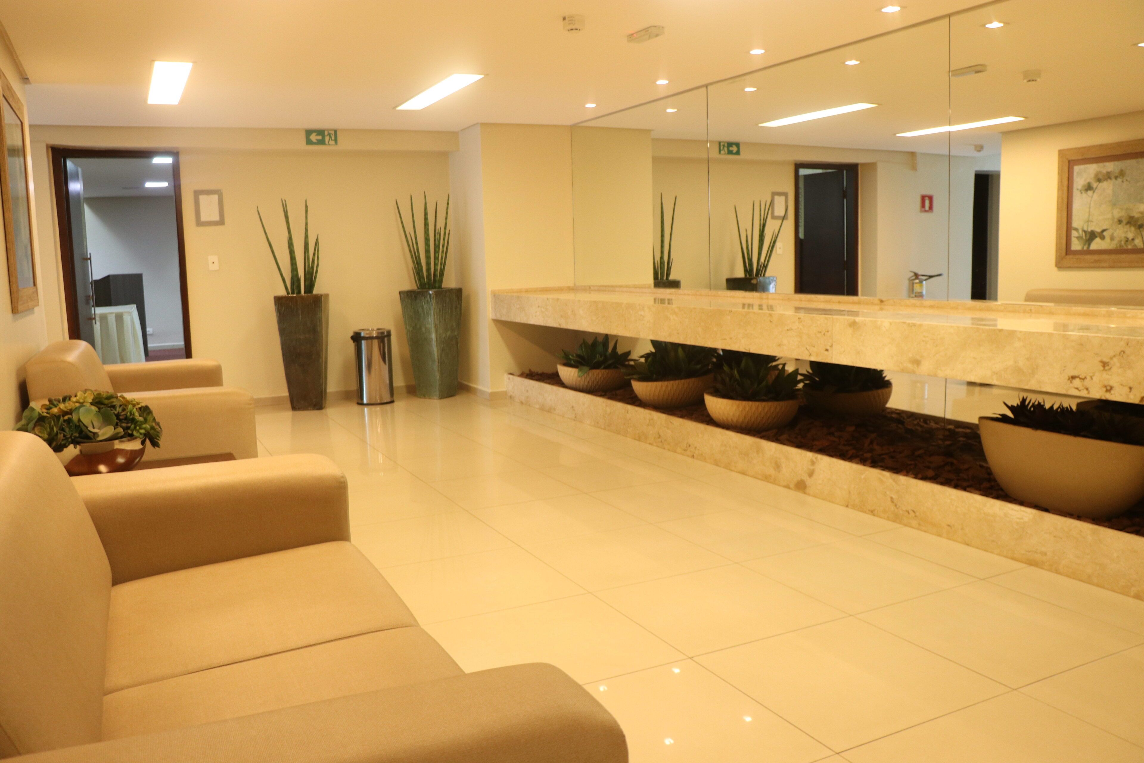 A reception area with a marble counter, several potted plants, and a seating area with sofas.