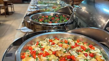 Un bufé con diversos platos, incluyendo un tazón grande de pollo con verduras y champiñones.