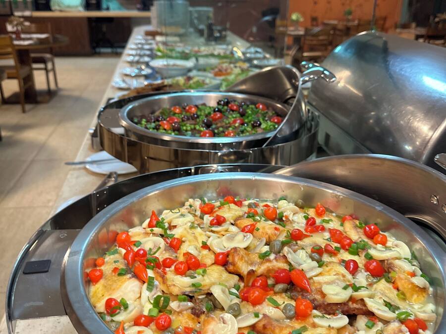 A buffet with various dishes, including a large bowl of chicken with vegetables and mushrooms.