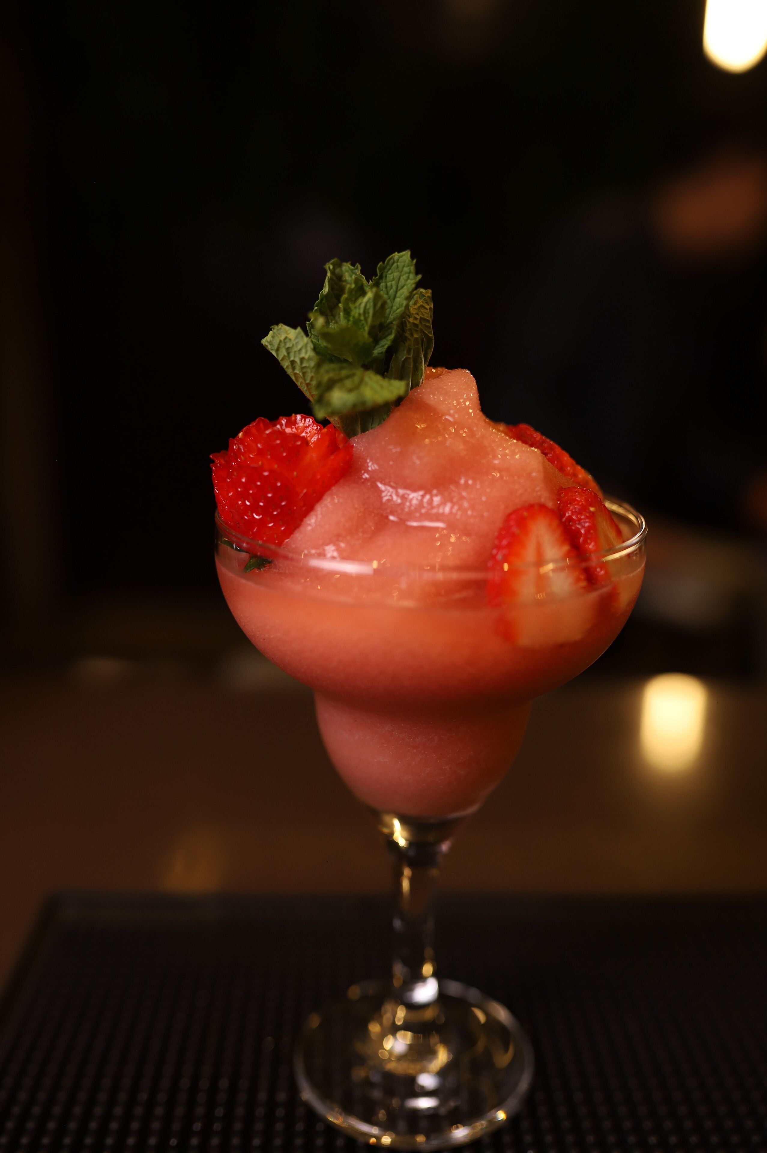A cocktail in a glass with ice and strawberries.