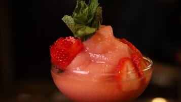 A cocktail in a glass with ice and strawberries.