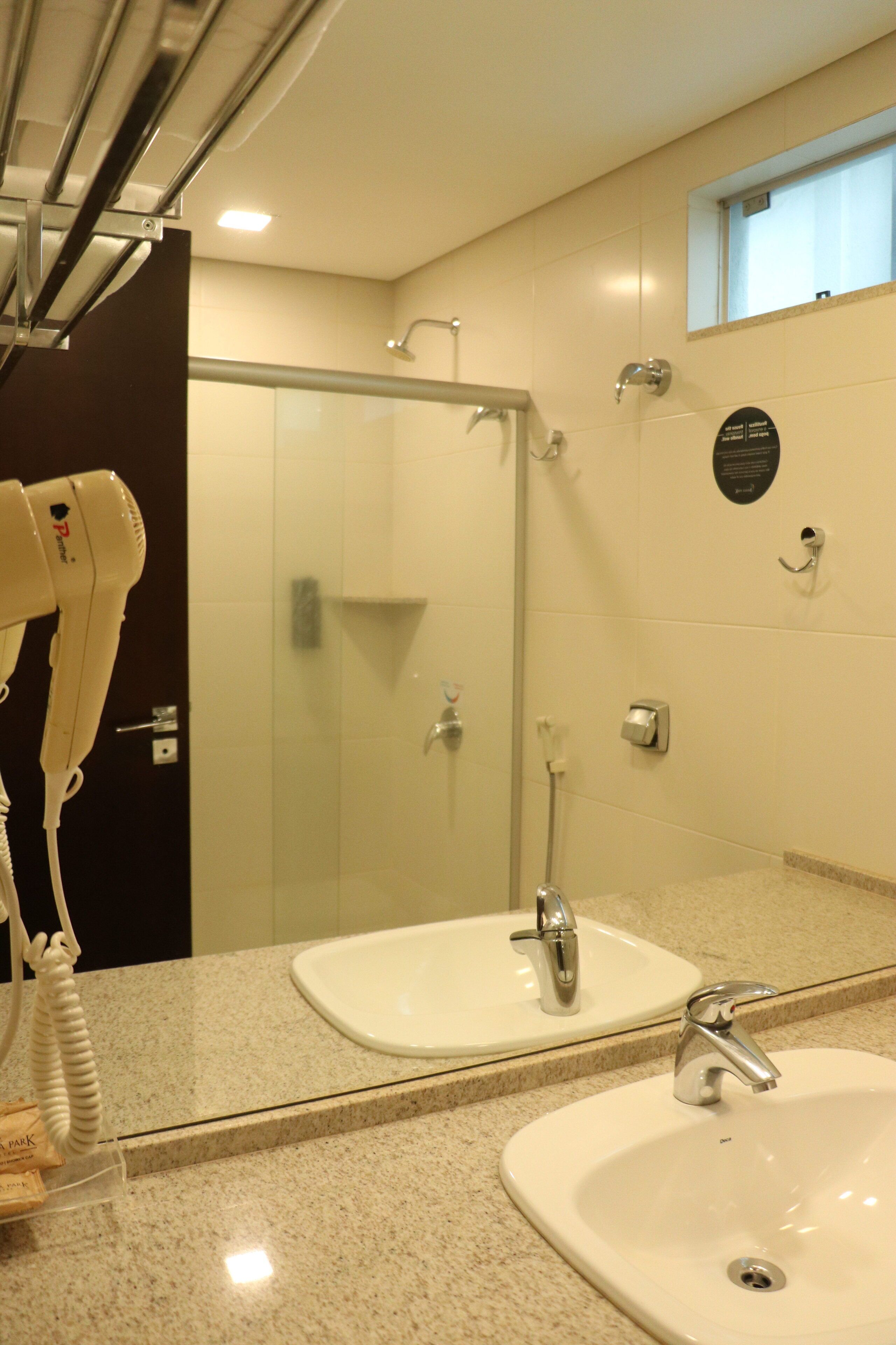 A bathroom with two sinks, a hairdryer, and a shower.