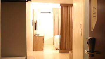 A hotel hallway with a bed, a desk, and a wardrobe.
