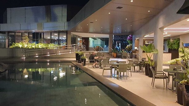 Un hall d’hôtel moderne doté d’une piscine, d’un espace extérieur aménagé et d’un escalier menant à un étage supérieur.