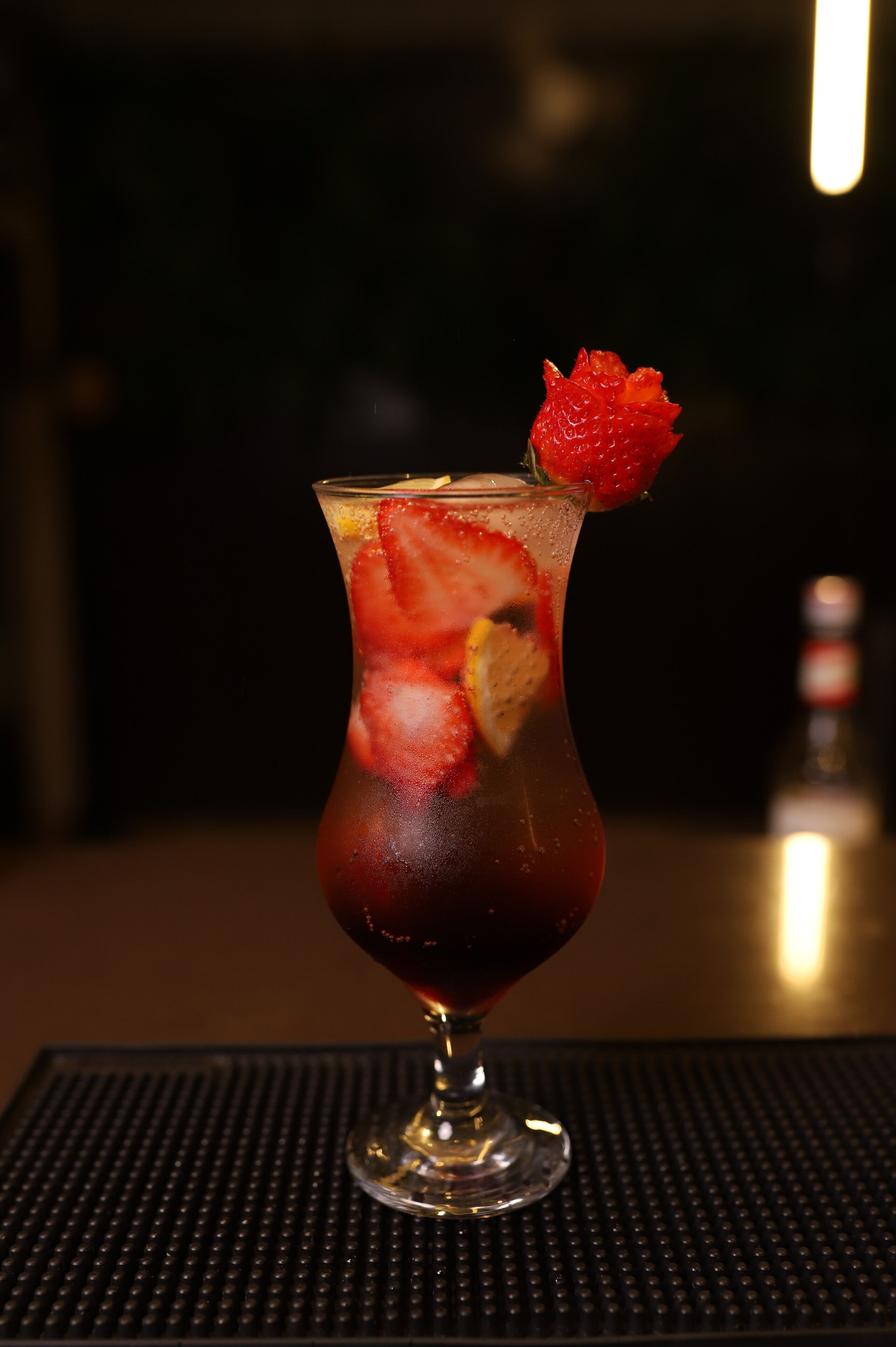 Ein Cocktailglas mit Erdbeerdeko auf einer strukturierten Tischplatte.