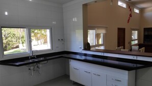 Une cuisine moderne avec des armoires blanches, des plans de travail noirs et une fenêtre donnant sur un jardin.