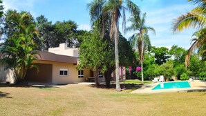 Une maison avec une piscine, entourée de palmiers et d’une pelouse bien entretenue.