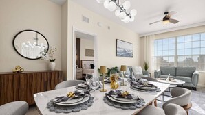 Comedor con una mesa dispuesta para seis personas, ventilador de techo y un gran ventanal con persianas.
