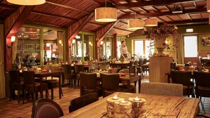 Un accogliente ristorante con travi in legno, lampade a sospensione e un'area bar.