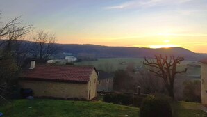Paisaje rural con atardecer, casas y un río.