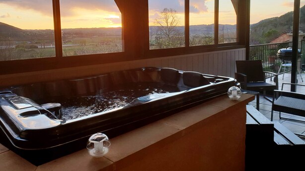 Un jacuzzi con vistas a un atardecer sobre un valle.