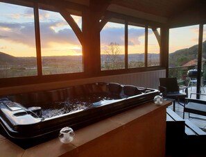 Un bain à remous avec vue sur un coucher de soleil au-dessus d’une vallée.