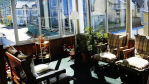 Una habitación iluminada por el sol con ventanas amplias, vistas a una piscina y varias sillas con una mesa.