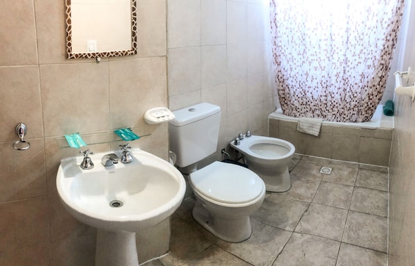 Un baño con lavamanos, dos inodoros y un bidé.