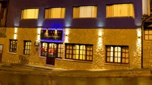 Hotel de varios pisos con fachada de piedra y ventanas iluminadas.
