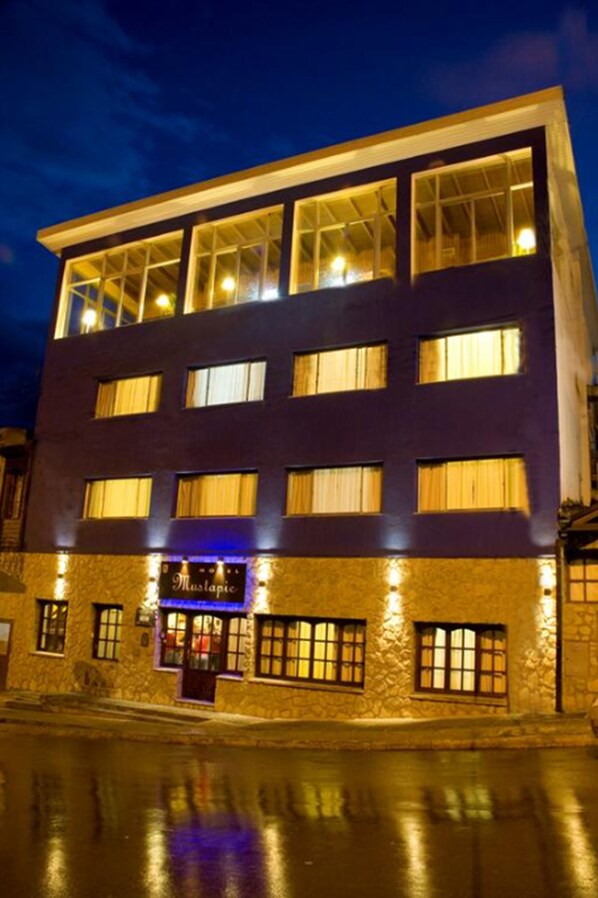 Un hotel a più piani con facciata in pietra e finestre illuminate.