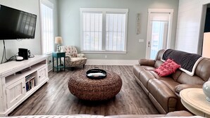 Una sala de estar con televisión, sofá, sillón y una mesa de centro.