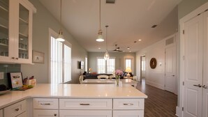 Una cocina amplia con una isla grande, armarios blancos e iluminación colgante.