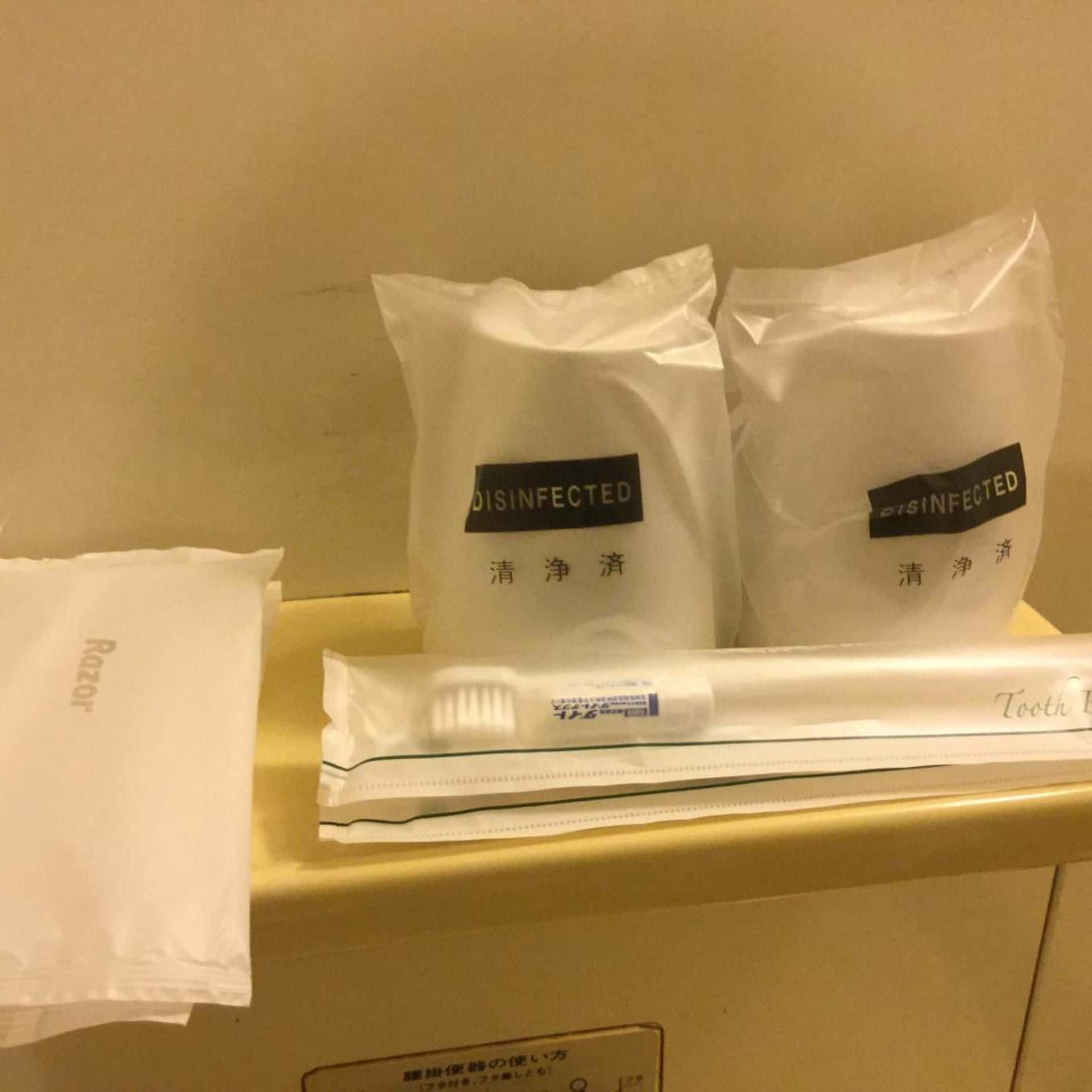 Deux sacs blancs portant l’étiquette « DÉSINFECTÉ » en caractères japonais, une boîte de mouchoirs blanche et un mouchoir blanc sur lequel est imprimé le mot « Razor ».