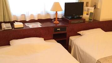 A hotel room with two beds, a desk with a lamp, a television, and a telephone.