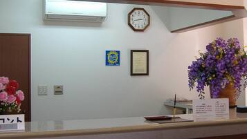 A reception desk with a clock, a framed certificate, and a vase of flowers.