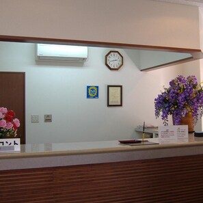 Una recepción con un reloj, un diploma enmarcado y un jarrón de flores.