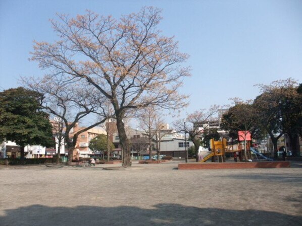 A park with a playground, trees, and buildings in the background. - Kisyaba Hotel (Kagoshima)