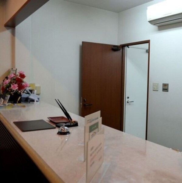 A reception desk with a flower arrangement, a black notepad, and a pen. - Kisyaba Hotel (Kagoshima)