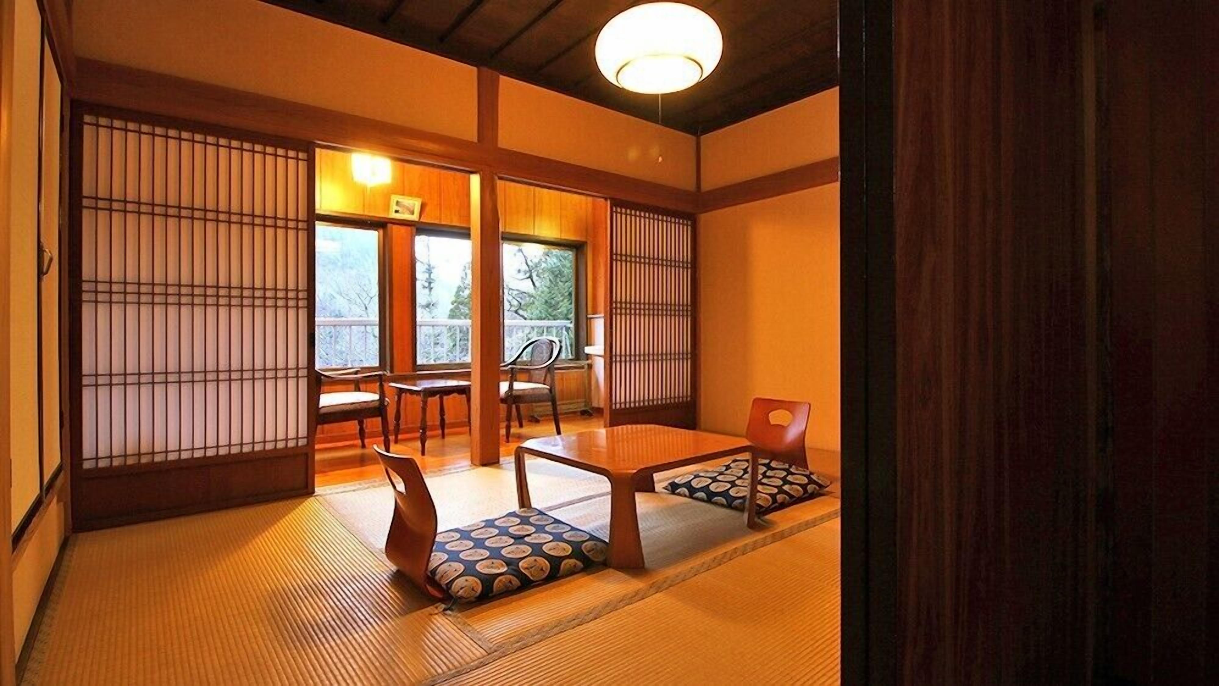 A traditional Japanese room with tatami flooring, sliding doors, and a low table with cushions.