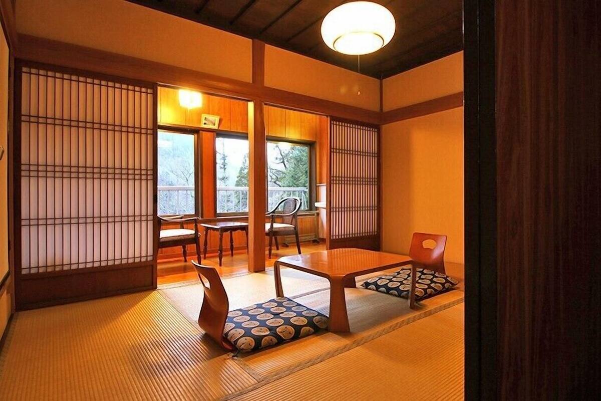 A traditional Japanese room with tatami flooring, sliding doors, and a low table with cushions.