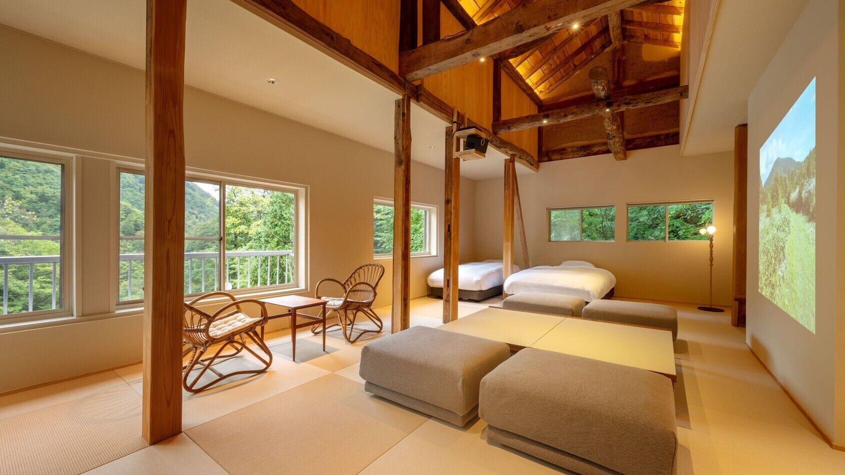 Una habitación amplia con ventanas grandes, una cama, un sofá y una pequeña mesa con sillas.