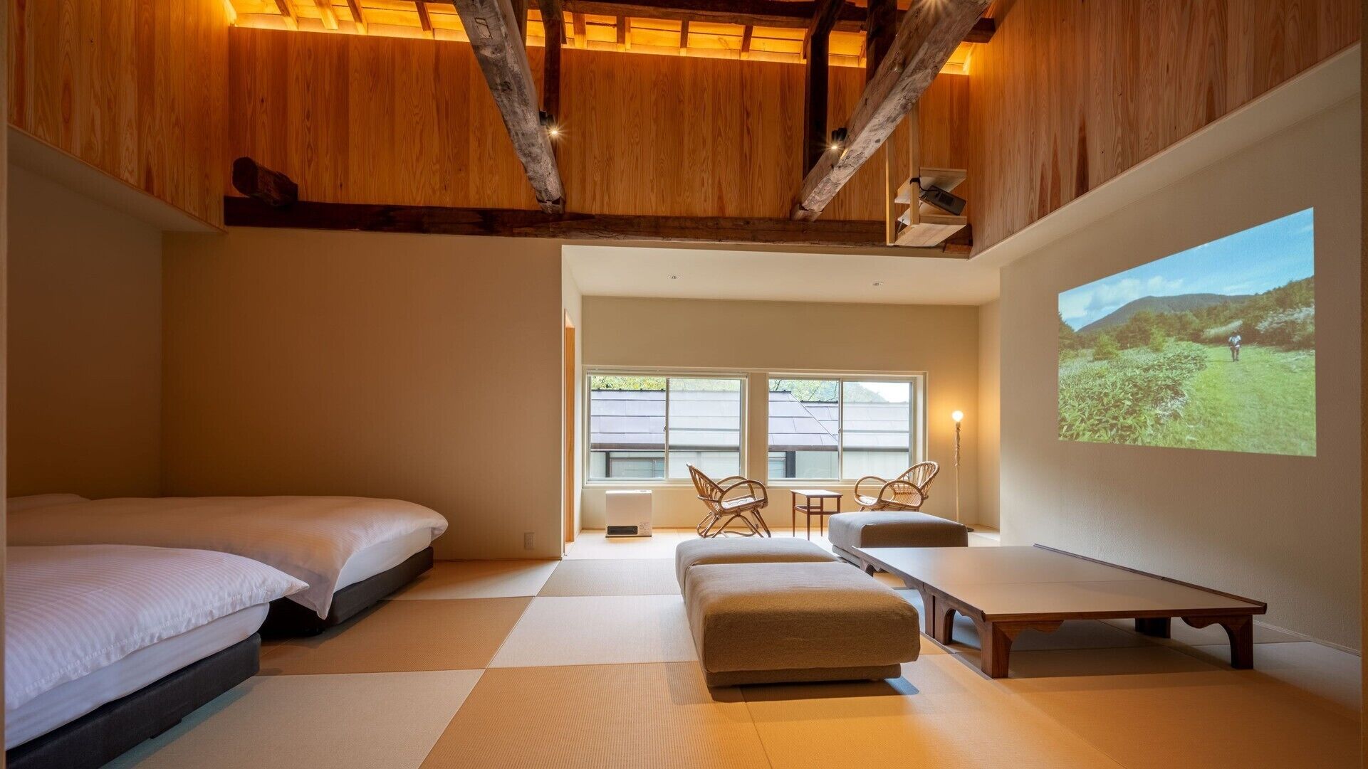 Un dormitorio con una cama, un sofá, una mesa y una pantalla proyectando un paisaje.