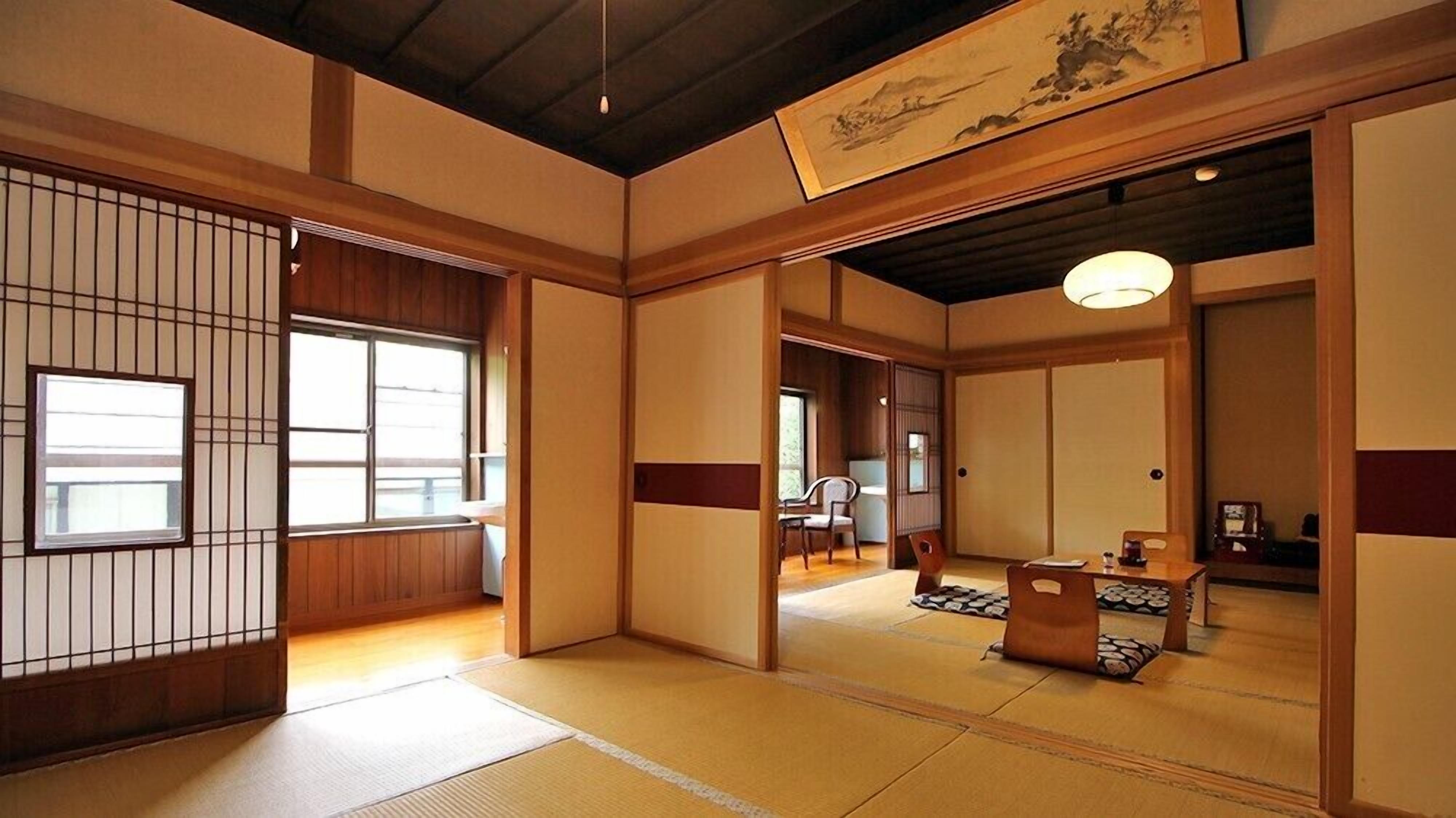 Una habitación japonesa tradicional con suelo de tatami, puertas correderas y una obra de arte colgante.